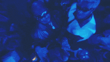 a group of people are standing in a dark room with blue lights behind them