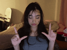 a girl with long dark hair is making a peace sign with her hands