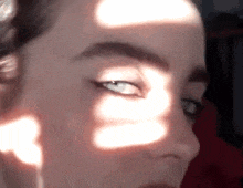 a close up of a woman 's face with a shadow on her eye
