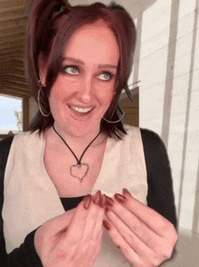 a woman wearing a necklace with a heart shaped pendant on it