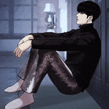 a man in a black turtleneck sits on the floor with his legs crossed