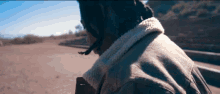 a person wearing a jacket with a fur collar is walking down a dirt road