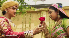 a man is giving a rose to a woman who is wearing a sony television logo