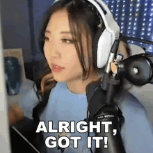 a woman wearing headphones and a blue shirt is sitting in front of a microphone .