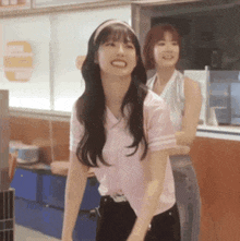 a woman in a pink shirt is smiling while standing next to another woman in a restaurant .