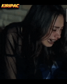 a woman is crying in front of a screen that says kiripac on it