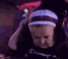 a baby wearing headphones and a headband is looking at the camera .