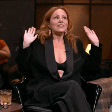 a woman in a black suit is sitting in a chair