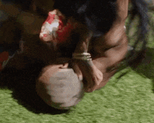 a man is laying on his back on the grass while a woman holds his head .