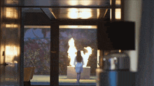a woman in a white dress is standing in front of a fire sculpture