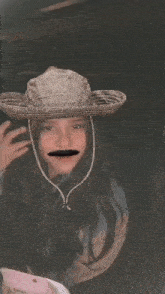 a woman wearing a sombrero and a fake mustache is making a funny face .