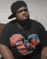 a man wearing a hat and a black shirt with a cartoon character on it