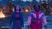 two women are dancing in front of a minecraft movie scene