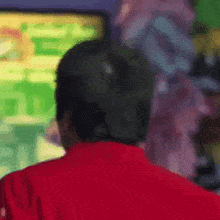 a man in a red shirt is playing a video game on a computer