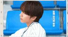 a man in a baseball uniform is sitting on a blue bleacher with chinese writing on it