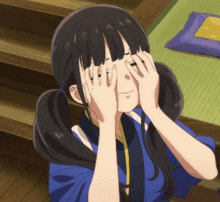 a girl covering her eyes with her hands in a blue shirt