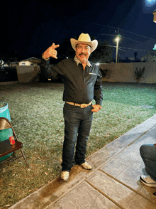 a man wearing a cowboy hat and a black shirt is giving the middle finger