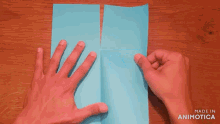 a person 's hands are holding a piece of blue paper .