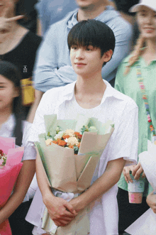 a young man in a white shirt holds a bouquet of flowers in his hands