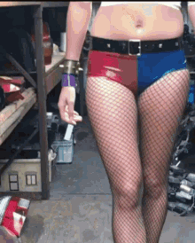 a woman in a harley quinn costume is wearing fishnet stockings and red and blue shorts