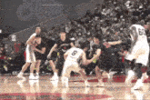 a group of basketball players are playing a game on a court with a crowd watching .