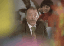 a man with a mustache in a suit and tie looks surprised
