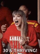 taylor swift is wearing a kansas city chiefs shirt while watching a game .