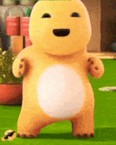 a yellow stuffed animal with a big belly is standing on a lush green field .