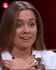 a woman with red nails is smiling and holding her hands to her chest in front of an a logo