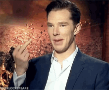 a man in a suit and white shirt is giving the middle finger in front of a sherlock speare poster