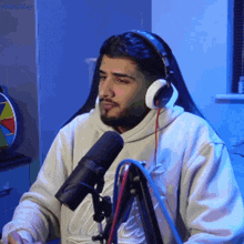 a man wearing headphones is sitting in front of a microphone with a blue background behind him