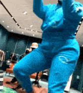a woman in a blue sweat suit is dancing in a store