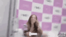 a blurry picture of a woman laying on a bed in front of a pink wall .