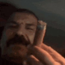 a man with a mustache is holding a piece of meat in his hands .