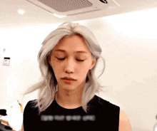 a woman with blonde hair is wearing a black tank top and looking down .