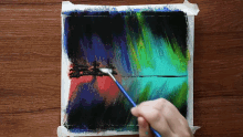 a painting of the aurora borealis is being painted on a wooden table