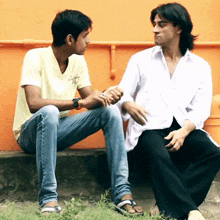 a man in a white shirt is sitting next to another man
