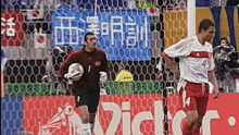 two soccer players on a field with a victor banner in the background