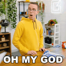 a man in a yellow hoodie says oh my god in front of a table