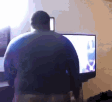 a man is standing in front of a television in a room