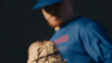 a man in a blue shirt is holding a glove