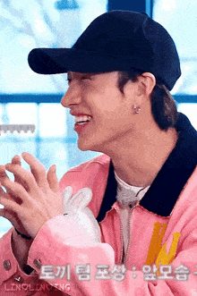 a man wearing a black hat and a pink jacket is clapping