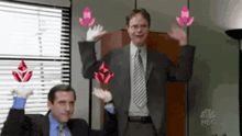 a man in a suit and tie is raising his arms in the air while another man watches