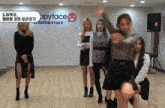 a group of girls are dancing in front of a happy face entertainment sign