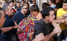 a woman in a colorful dress is being held by a group of men .
