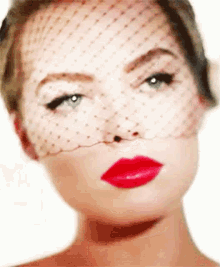 a woman wearing a veil on her face and red lipstick .