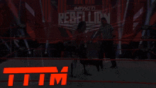 a wrestler in a ring with a referee and the word rebellion