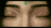a close up of a person 's face with their eyes closed and a green leaf on their forehead