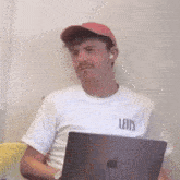 a man wearing a white levis shirt is sitting in front of an apple laptop computer .