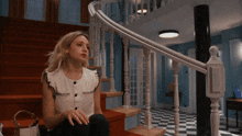 a woman is sitting on a set of stairs with a checkered floor